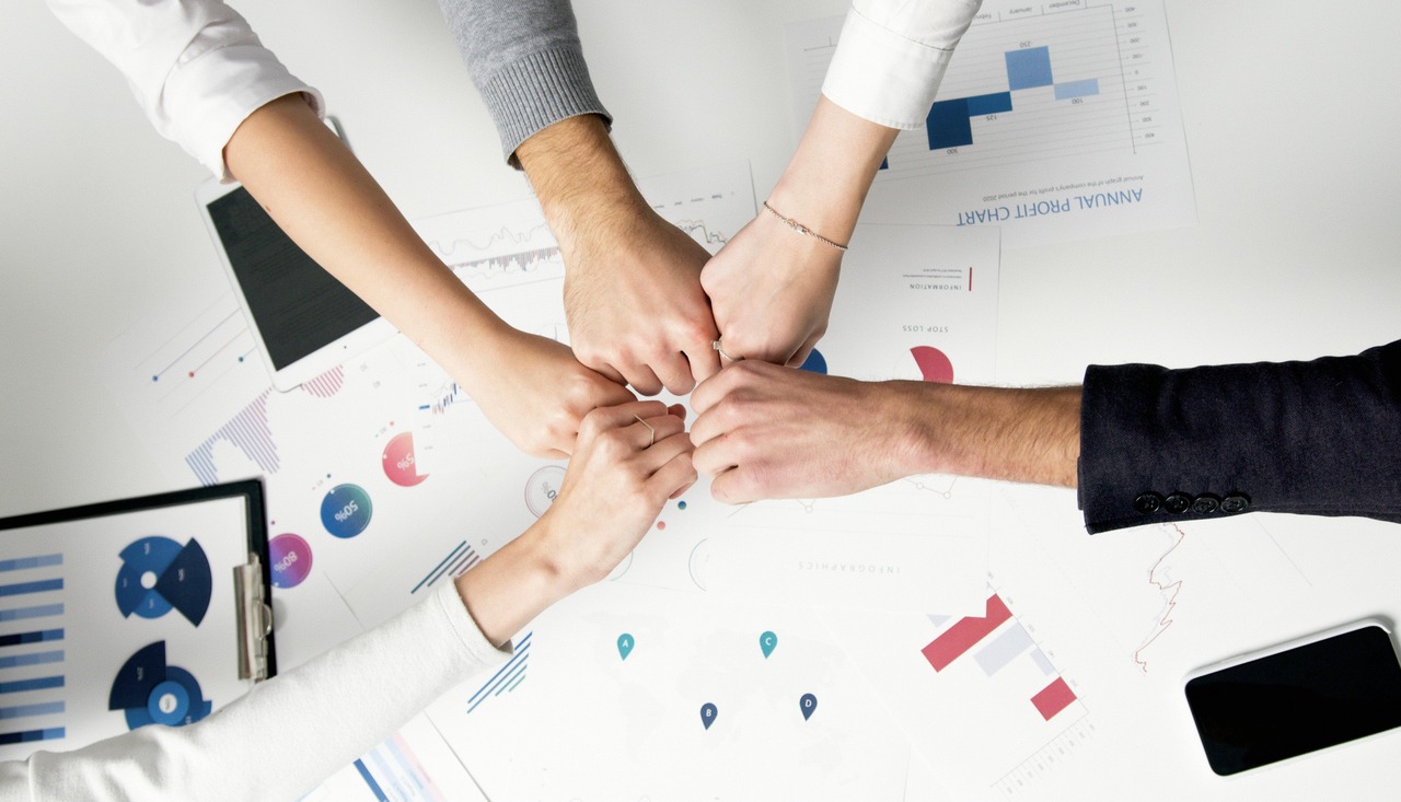 A team with hands together over a desk